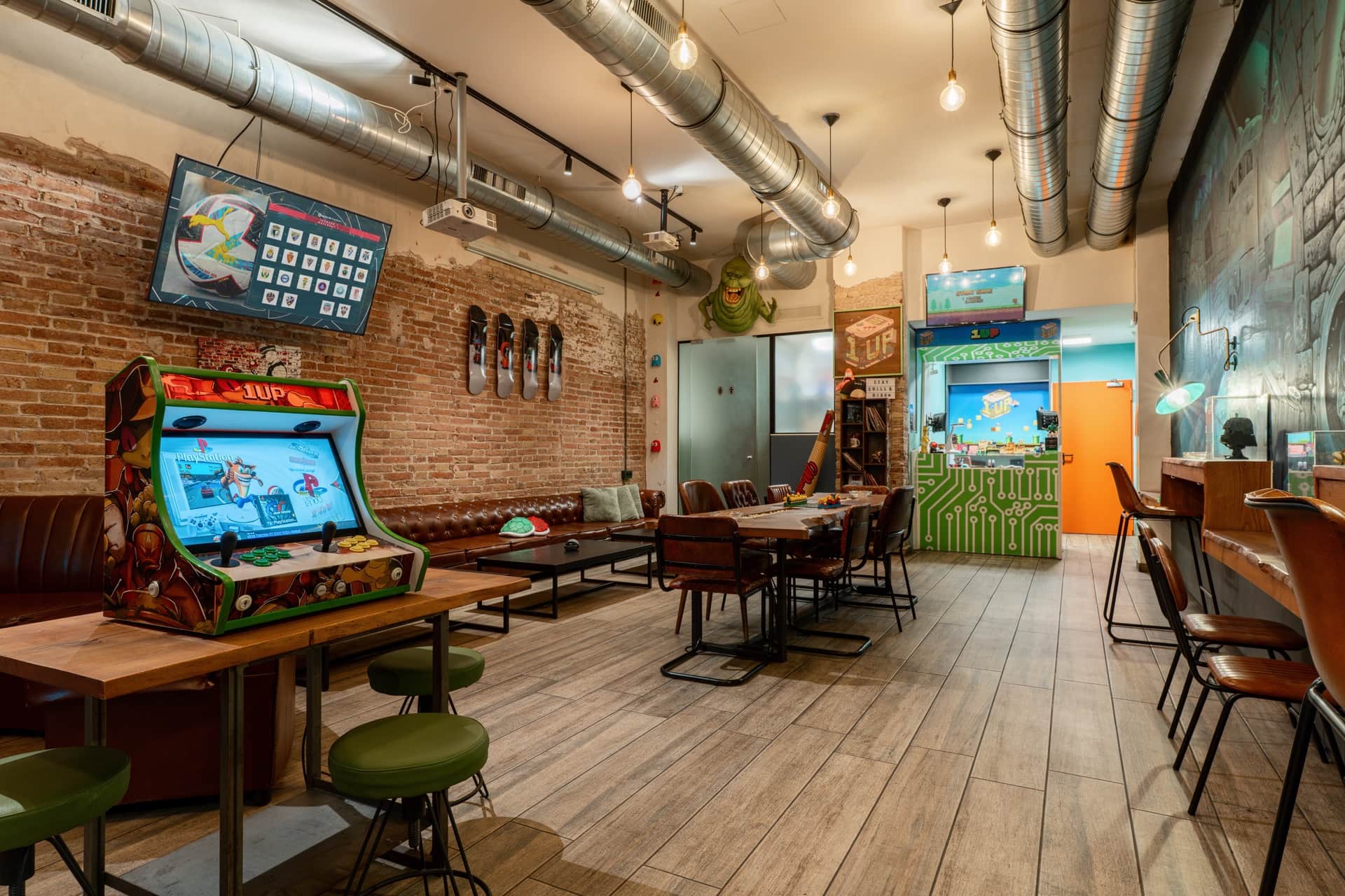 Máquina arcade y zona de descanso en el club social 1UP Barcelona